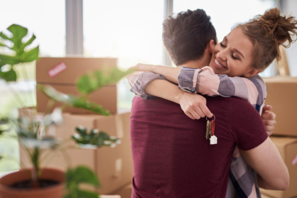 Happy couple hugging with keys of new house